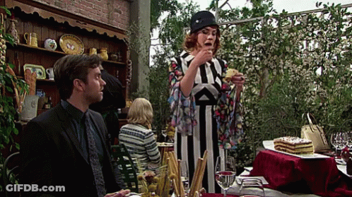 A Woman In A Striped Dress Is Eating A Piece Of Cake While A Man Looks On GIF
