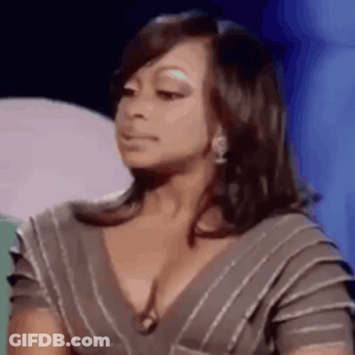 A Woman In A Striped Dress Is Making A Funny Face While Sitting On A Stage . GIF
