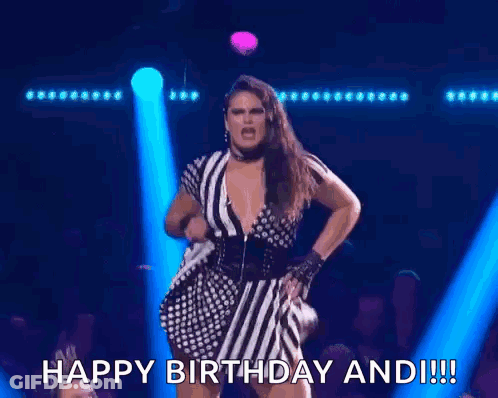 A Woman In A Striped Dress Is Singing Into A Microphone And Says Happy Birthday And !! GIF