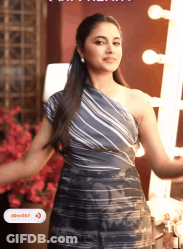 A Woman In A Striped One Shoulder Dress Is Standing In Front Of A Mirror With Ddev007 Written On The Bottom Right GIF