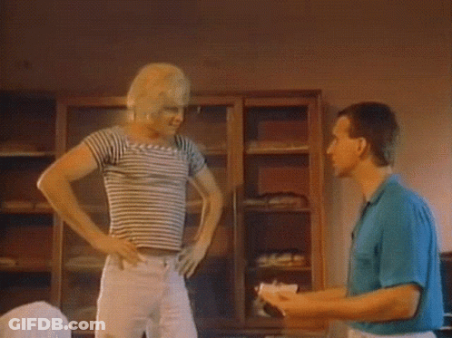 A Woman In A Striped Shirt And White Pants Is Dancing In A Room GIF