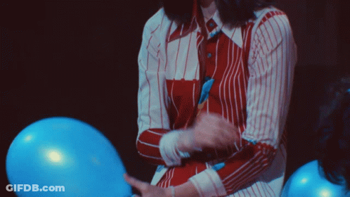 A Woman In A Striped Shirt Is Holding A Blue Balloon GIF