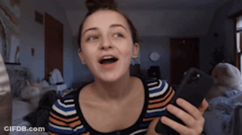 A Woman In A Striped Shirt Is Holding A Cell Phone GIF