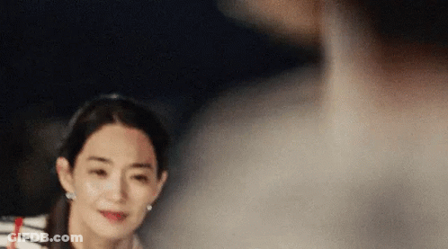 A Woman In A Striped Shirt Is Looking At A Man In A White Shirt . GIF
