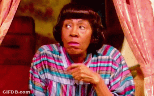 A Woman In A Striped Shirt Is Making A Funny Face While Sitting In Front Of A Window . GIF