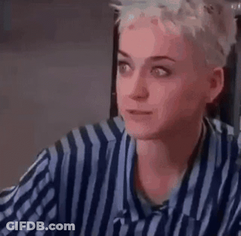 A Woman In A Striped Shirt Is Sitting At A Table Drinking A Glass Of Wine . GIF