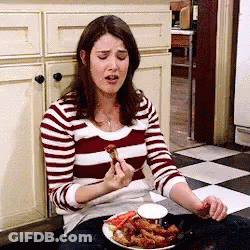 A Woman In A Striped Shirt Is Sitting On The Floor Eating Food . GIF