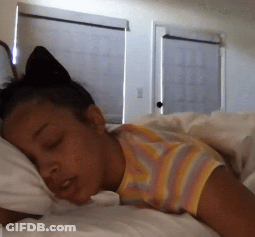 A Woman In A Striped Shirt Is Sleeping In A Bed GIF