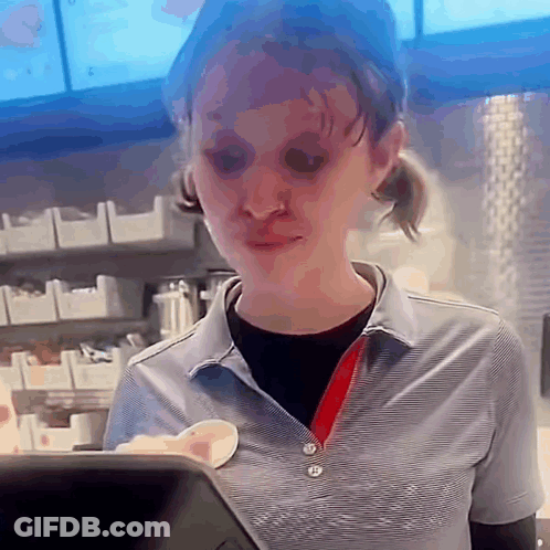 A Woman In A Striped Shirt Is Standing In Front Of A Counter In A Fast Food Restaurant . GIF