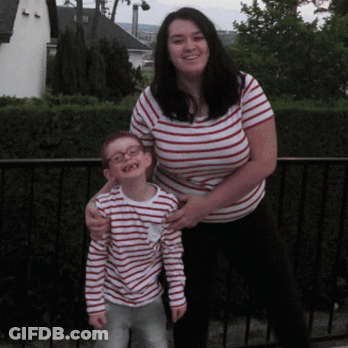 A Woman In A Striped Shirt Stands Next To A Young Boy GIF
