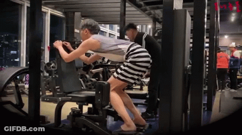 A Woman In A Striped Skirt Is Doing Exercises In A Gym GIF