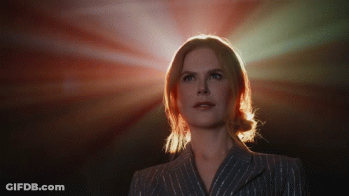 A Woman In A Striped Suit Is Looking Up At The Sun GIF