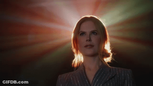 A Woman In A Striped Suit Stands In Front Of A Red Light GIF