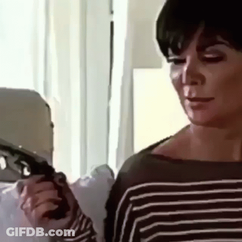 A Woman In A Striped Sweater Is Holding A Gun In Her Hand . GIF