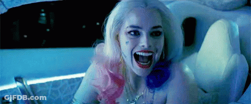 A Woman In A Suicide Squad Costume Is Sitting In A Tub With Her Mouth Open . GIF