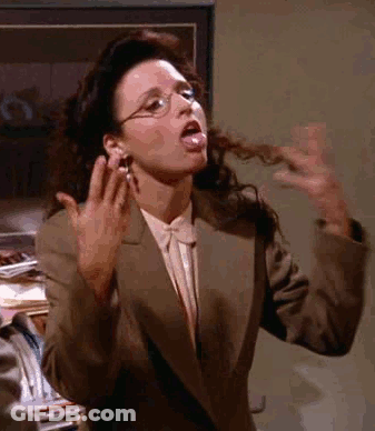 A Woman In A Suit And Glasses Is Sticking Her Tongue Out And Making A Funny Face . GIF