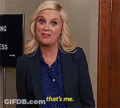 A Woman In A Suit And Polka Dot Shirt Is Standing In Front Of A Sign That Says `` That 'S Me '' . GIF