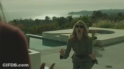 A Woman In A Suit And Sunglasses Is Screaming At A Man In Front Of A Pool . GIF