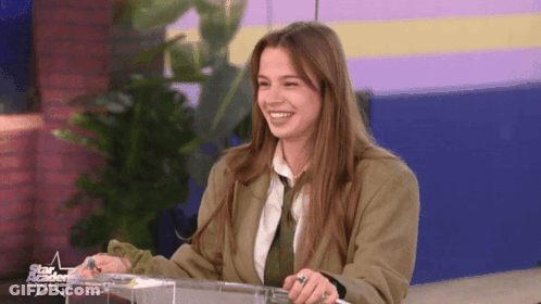 Woman In Suit And Tie Smiling In Front Of Star Academy Sign GIF
