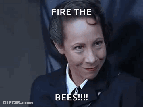 A Woman In A Suit And Tie Is Smiling With The Words `` Fire The Bees '' Written Above Her . GIF