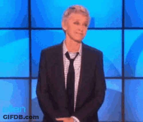 A Woman In A Suit And Tie Is Standing In Front Of A Blue Screen With The Word Ellen On It GIF