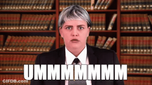 Woman In Suit And Tie In Front Of Bookshelf Says Ummmmmm GIF