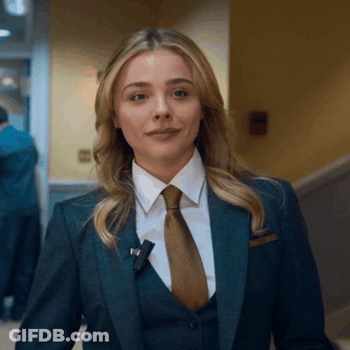 A Woman In A Suit And Tie With A Name Tag That Says ' Amanda ' GIF