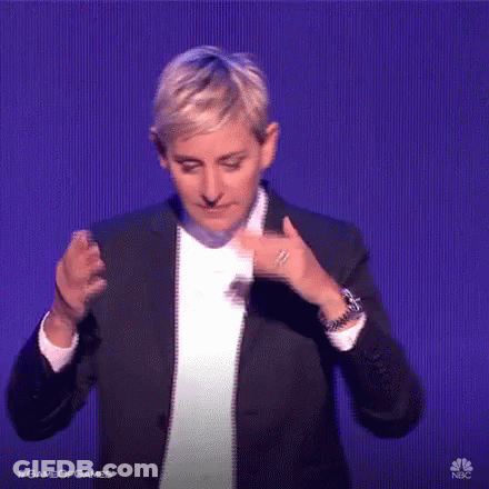 A Woman In A Suit And White Shirt Is Dancing On A Stage In Front Of A Blue Background . GIF