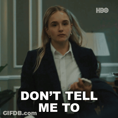 A Woman In A Suit And White Shirt Is Holding A Cell Phone And Says " Don 'T Tell Me To " GIF