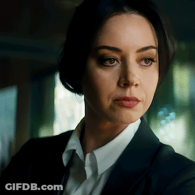 A Woman In A Suit And White Shirt Is Looking At The Camera With A Serious Look On Her Face . GIF