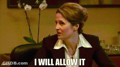 A Woman In A Suit And White Shirt Is Sitting In A Chair And Saying I Will Allow It . GIF