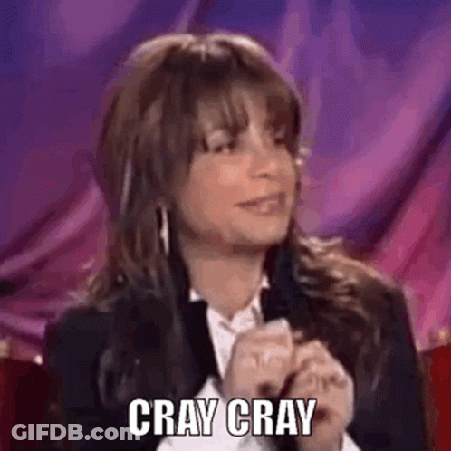 A Woman In A Suit And White Shirt Is Sitting In Front Of A Purple Curtain And Says `` Cray Cray '' . GIF