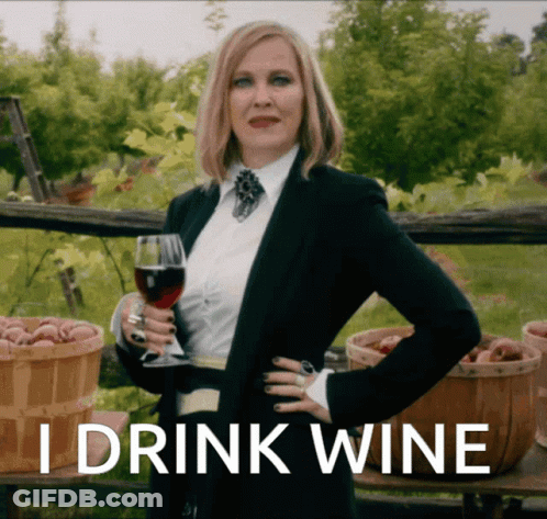 A Woman In A Suit Holding A Glass Of Wine With The Words I Drink Wine Above Her GIF