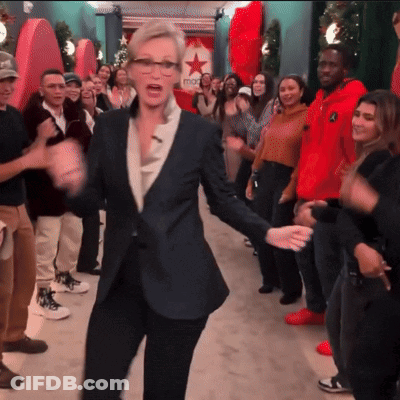 A Woman In A Suit Is Dancing In Front Of A Macys Sign GIF