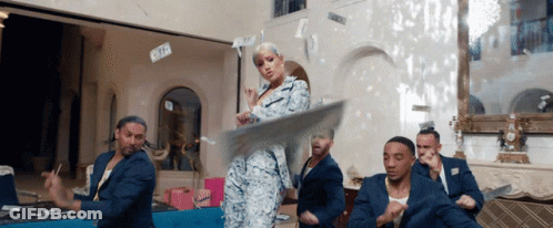 A Woman In A Suit Is Dancing With A Group Of Men GIF