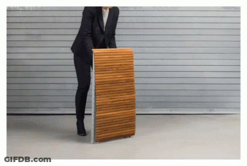 A Woman In A Suit Is Holding A Wooden Plank GIF