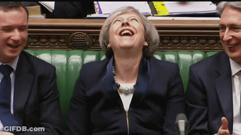 A Woman In A Suit Is Laughing While Sitting Next To Two Men GIF