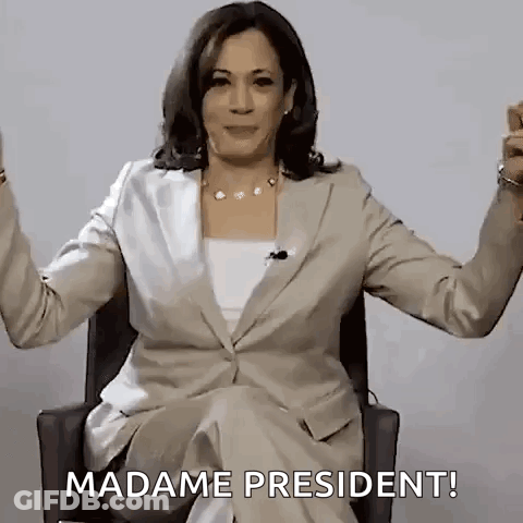 A Woman In A Suit Is Sitting In A Chair With Her Arms Outstretched And Saying `` Madame President '' . GIF