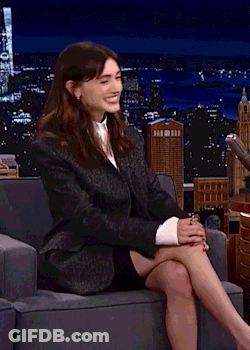 A Woman In A Suit Is Sitting In A Chair With Her Legs Crossed . GIF