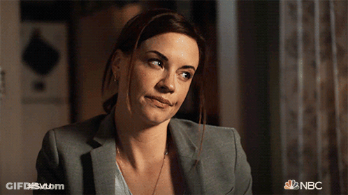 A Woman In A Suit Is Smiling With The Nbc Logo In The Background GIF