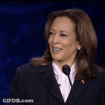 A Woman In A Suit Is Speaking Into A Microphone While Smiling GIF