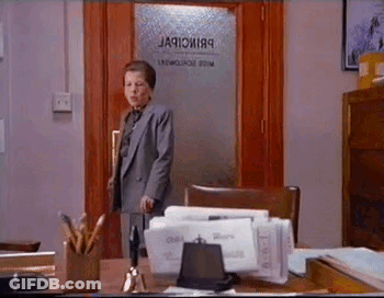 A Woman In A Suit Is Standing In Front Of A Door That Says ' Jacobi89 ' On It . GIF