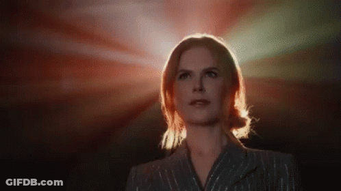A Woman In A Suit Is Standing In Front Of A Red Light And Looking Up . GIF