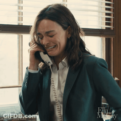 A Woman In A Suit Is Talking On A Phone With Ella Mccay Written On The Bottom GIF
