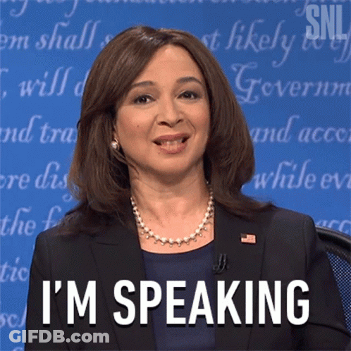 A Woman In A Suit Says I 'M Speaking In Front Of A Blue Background GIF