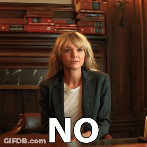 A Woman In A Suit Sits At A Desk With The Word No Written On Her Face GIF