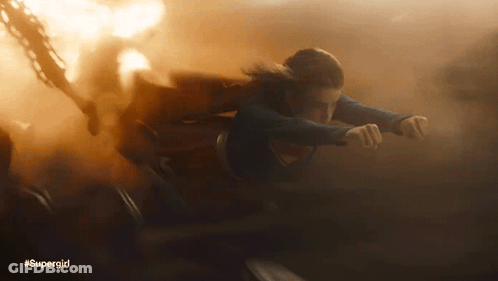 A Woman In A Supergirl Costume Is Flying Through Smoke GIF