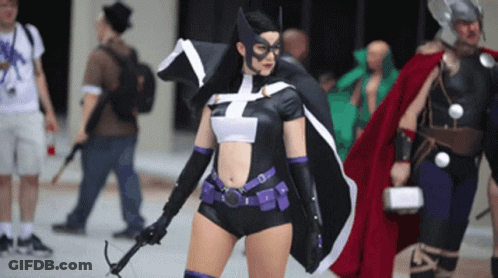 A Woman In A Superhero Costume Is Holding A Bow GIF