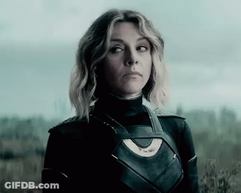 A Woman In A Superhero Costume Is Standing In A Field . GIF