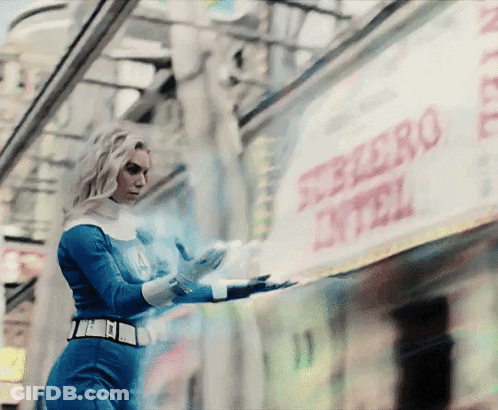 A Woman In A Superhero Costume Is Standing In Front Of A Sign That Says Ferrero GIF